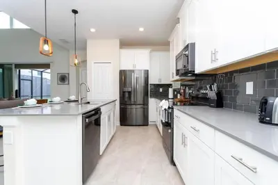 a kitchen with white cabinets and a stainless steel refrigerator at Gorgeous 5BDR Family with Pool at Storey Lake 2767 O in Kissimmee