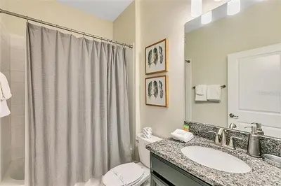 a bathroom with a sink and a toilet and a mirror at 5 Bed Storey Lake Home Lazy River Resort villa in Kissimmee