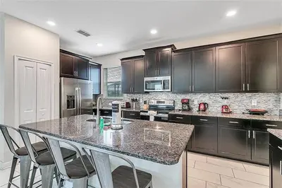 a kitchen with a large island with chairs in it at 5 Bed Storey Lake Home Lazy River Resort villa in Kissimmee