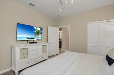 a white bedroom with a flat screen tv on a white wall at Amazing Game Room Your Kids Will Love! villa in Kissimmee