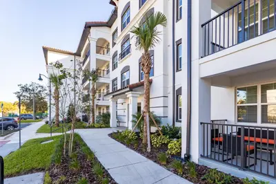 a building with palm trees and a sidewalk at Vista Cay Resort by Millenium at Universal Blvd. in Orlando