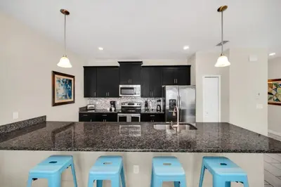 a kitchen with a counter with blue stools at Spacious and Luxurious Home With Splash Pool, Close to Disney #4ST804 in Kissimmee