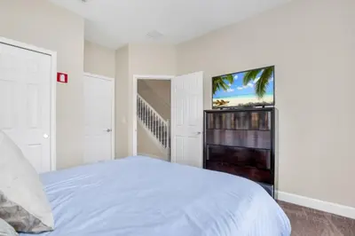 a white bedroom with a bed and a flat screen tv at 3 bed Town Home With Splash Pool! townhouse in Orlando