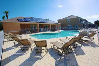 a swimming pool with chairs and a table and a building at 3 bed Town Home With Splash Pool! townhouse in Orlando