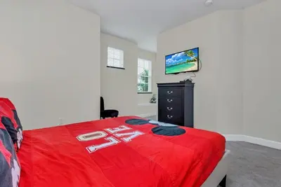a bedroom with a red bed and a black dresser at Serenity 3 Bed Townhome townhouse in Orlando