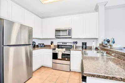a kitchen with white cabinets and a stainless steel refrigerator at Modern 3BR - Near Disney - Pool in Orlando