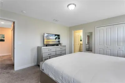 a white bedroom with a bed and a tv at Storey Lake 4 Bedroom Townhome townhouse in Kissimmee