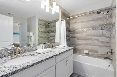 a bathroom with two sinks and a shower and a mirror at Storey Lake 4 Bedroom Townhome townhouse in Kissimmee