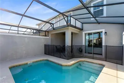 a swimming pool in front of a house at Storey Lake 4 Bedroom Townhome townhouse in Kissimmee
