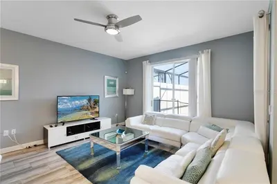 a living room with a white couch and a tv at Storey Lake 4 Bedroom Townhome townhouse in Kissimmee