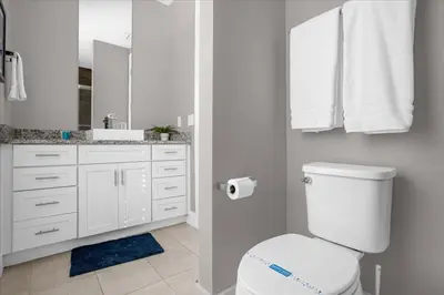 a white bathroom with a toilet and a sink at Magical Vacation Home 3 min from Disney in Orlando
