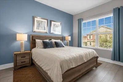a bedroom with a bed with blue walls and a window at Magical Vacation Home 3 min from Disney in Orlando