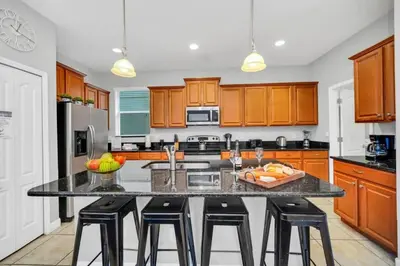 a kitchen with wooden cabinets and a island with bar stools at Appealing, Large 5BD Home Close to Themed-Parks #5PP961 in Kissimmee