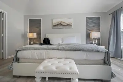 a white bedroom with a white bed with a white ottoman at Spacious 6BR Villa Pool Parking Near Disney World in Orlando