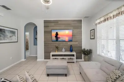 a living room with a couch and a tv on a wall at Spacious 6BR Villa Pool Parking Near Disney World in Orlando