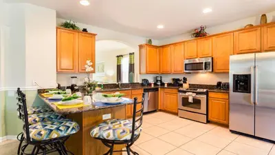 a kitchen with wooden cabinets and stainless steel appliances at Spacious 6BR Villa with Pool SPA 3 Miles to Disney in Orlando