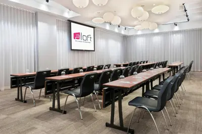 a conference room with tables and chairs and a screen at Aloft Orlando Downtown in Orlando