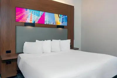 a bedroom with a large bed with a tv above it at Aloft Orlando Downtown in Orlando