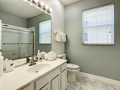 a bathroom with a sink and a toilet and a mirror at Luxury Family Villa Pool Hot Tub Close to Disney in Orlando