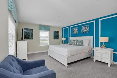a bedroom with a bed and a blue accent wall at LAKEVIEW Home w Private Pool FREE Water Park in Kissimmee