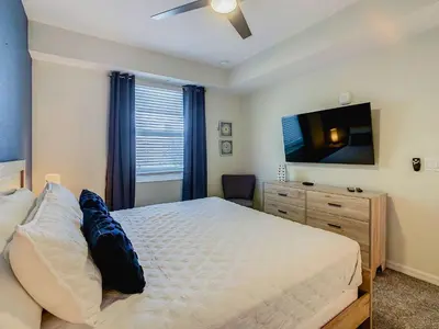 a bedroom with a bed and a flat screen tv at Cute Lakeview 2BR Condo with 2 Clubhouses in Kissimmee