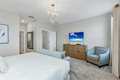 a bedroom with a bed and a chair and a chandelier at Lovely Private Pool Villa wFREE Resort Access in Kissimmee