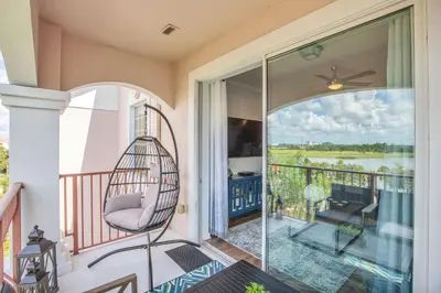 a balcony with a swinging chair and a view of the water at Top floor condo with view of lake, pool and fireworks! Next to Convention Center! in Orlando