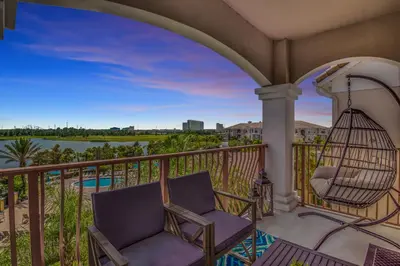 a patio with a swing and a chair on a balcony at Top floor condo with view of lake, pool and fireworks! Next to Convention Center! in Orlando