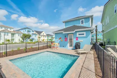 a swimming pool in front of a blue house at 8044 Sandy Toes Way in Orlando