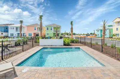 a swimming pool with a fence and palm trees at 8044 Sandy Toes Way in Orlando