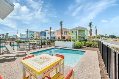a pool with a table and chairs and houses at 8044 Sandy Toes Way in Orlando