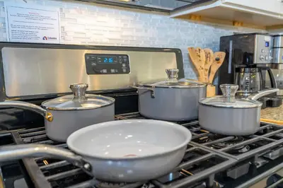 three pots and pans on a stove in a kitchen at Themed Disney House 5 min to Disney Parks, Heated Pool, Jacuzzi, Gym and more in Orlando