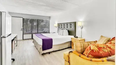a hotel room with a bed and a chair at Home 1 Suites Extended Stay - Kissimmee in Kissimmee
