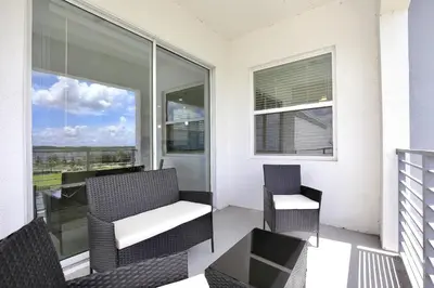 a balcony with two chairs and a table and windows at Great apartment in Storey Lake resort with great amenities next to Disney! in Kissimmee