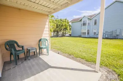 two chairs sitting on the porch of a house with a yard at Royal Palm Bay 3 Bedroom Condo Resort Pool 10 Min Disney in Kissimmee