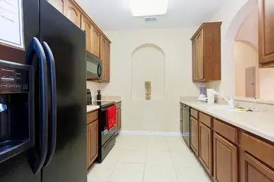 a kitchen with a black refrigerator and wooden cabinets at 2Br 2Bath Condo Balcony 5min Conv Center 1496ft in Orlando