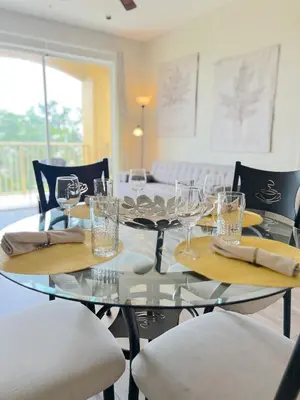 a glass table with chairs and wine glasses on it at 2Br 2Bath Condo Balcony 5min Conv Center 1496ft in Orlando