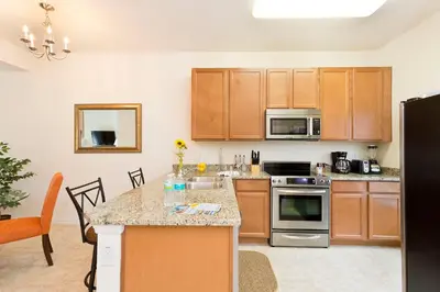a kitchen with wooden cabinets and a counter top at 3Br 3Bath Townhome BBQ Pool 15min Disney 1291ft in Kissimmee