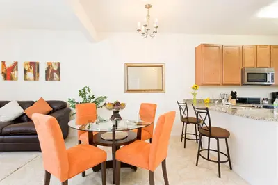a kitchen and living room with a table and chairs at 3Br 3Bath Townhome BBQ Pool 15min Disney 1291ft in Kissimmee