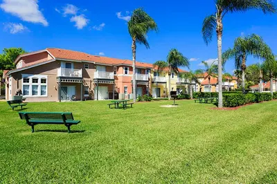 a park with benches in front of a large building at Family Getaway Townhome at Lake Berkley 15min to Disney in Kissimmee
