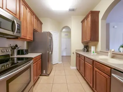 a kitchen with wooden cabinets and a stainless steel refrigerator at 3Br 2Bath Condo Balcony 5min Conv Center 1410ft in Orlando
