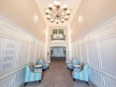 a hallway with blue chairs and a chandelier at Spacious Vista Cay Condo near Universal Studios in Orlando