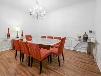 a dining room table with orange chairs and a chandelier at 4Br 2Bath Condo Balcony 5min Conv Center 2020ft in Orlando