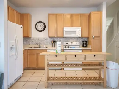 a kitchen with wooden cabinets and a white refrigerator at 5Br 3Bath Private Townhome 13min Disney 1496ft in Kissimmee