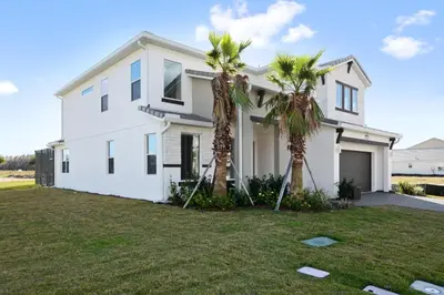 a white house with two palm trees in the yard at 5Br 5Bath Pvt Home BBQ Pool 15min Disney 3056ft in Kissimmee