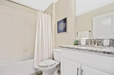 a white bathroom with a toilet and a sink at 5Br 5Bath Pvt Home BBQ Pool 10min Disney 3077ft in Kissimmee