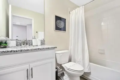 a white bathroom with a toilet and a sink at 5Br 5Bath Pvt Home BBQ Pool 10min Disney 3077ft in Kissimmee