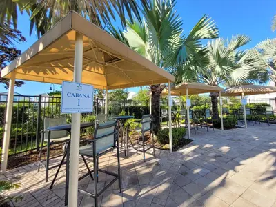 a patio with tables and chairs and umbrellas at 5Br 5Bath Pvt Home BBQ Pool 10min Disney 3077ft in Kissimmee