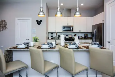 a kitchen with a bar with chairs and a counter top at 3 BR 3BA 1678ft 5min Disneyworld Resort style in Orlando