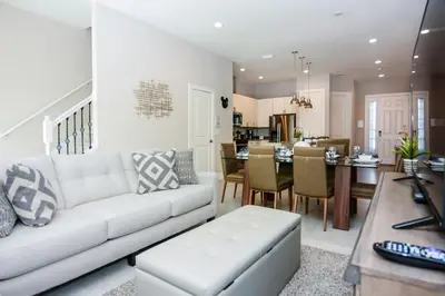 a living room with a white couch and a dining room at 3 BR 3BA 1678ft 5min Disneyworld Resort style in Orlando
